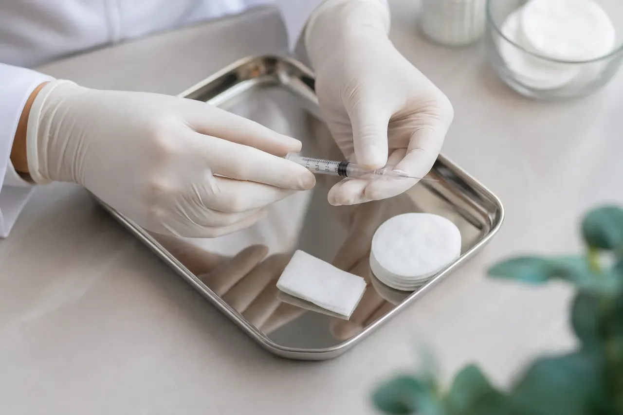 Mani guantate di un medico che preparano una siringa sottile su un vassoio sterile